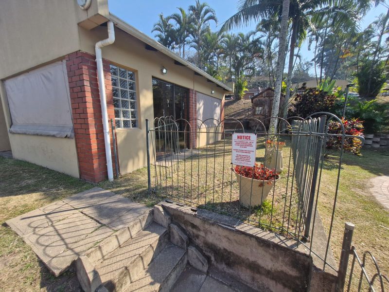 Rear exterior view of the townhouse featuring a brick and plaster facade, sliding glass doors, and a fenced garden area with concrete steps.