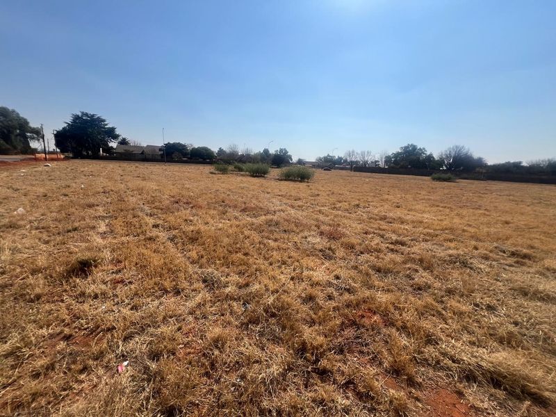 A wide-angle view of a vacant residential plot featuring dry grassland and open space, suitable for future development.