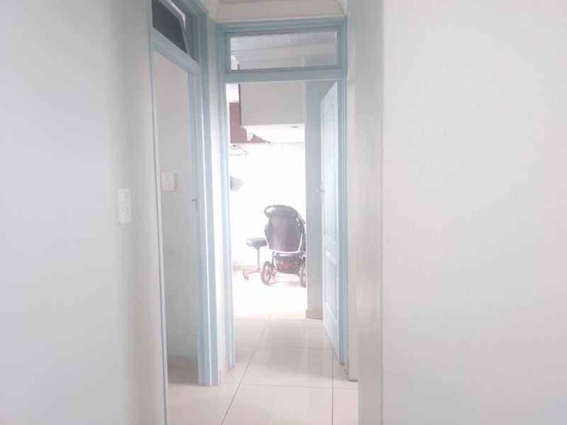 A functional hallway featuring tiled flooring and internal doors with transom windows, providing access to adjacent rooms.