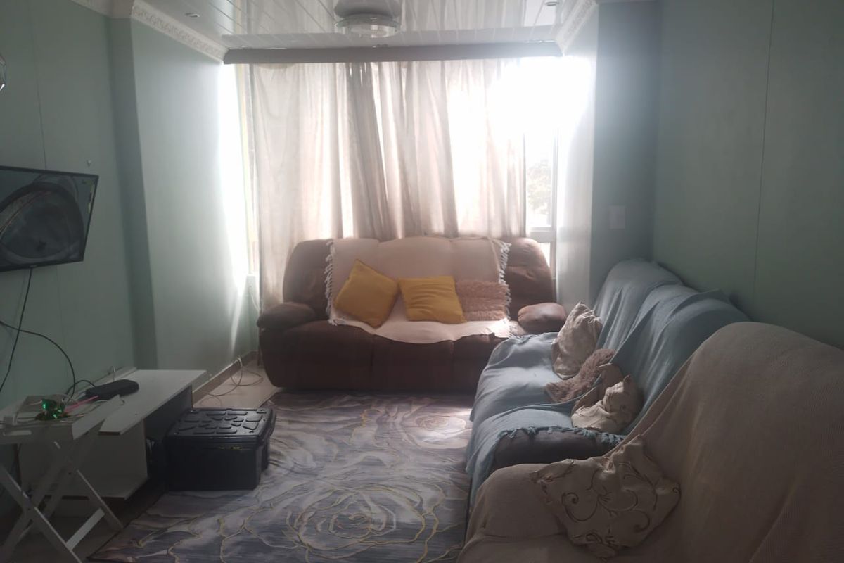 A living room featuring a glossy ceiling with crown molding and tiled flooring, illuminated by natural light from a large window.