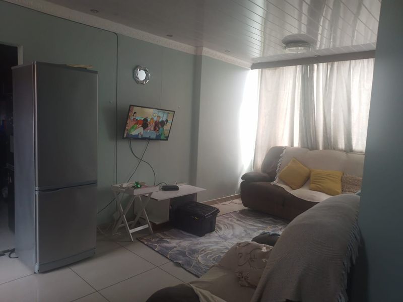 A living room featuring tiled flooring, coved ceiling cornices, and glossy ceiling panels with recessed lighting.
