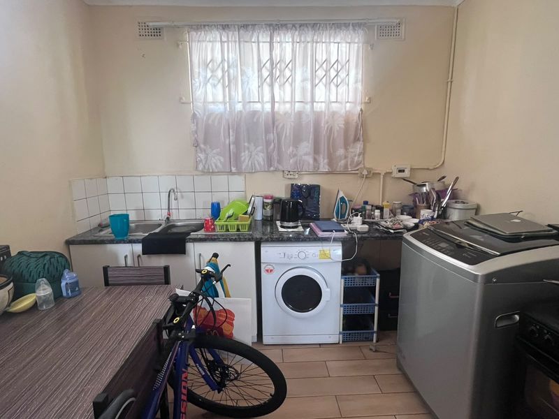 Functional laundry area featuring a double basin sink, tiled splashback, and built-in cabinetry with space for laundry appliances.