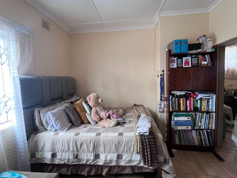 A bedroom featuring tiled flooring and a ceiling vent, showing signs of wear on the wall surfaces.