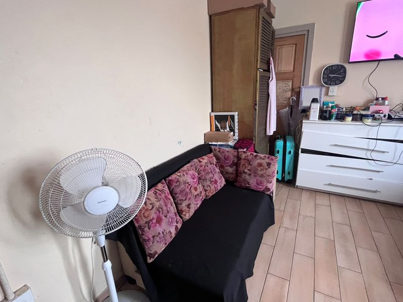 A living area featuring tiled flooring and a wooden door, currently showing signs of wear and requiring cosmetic updates.