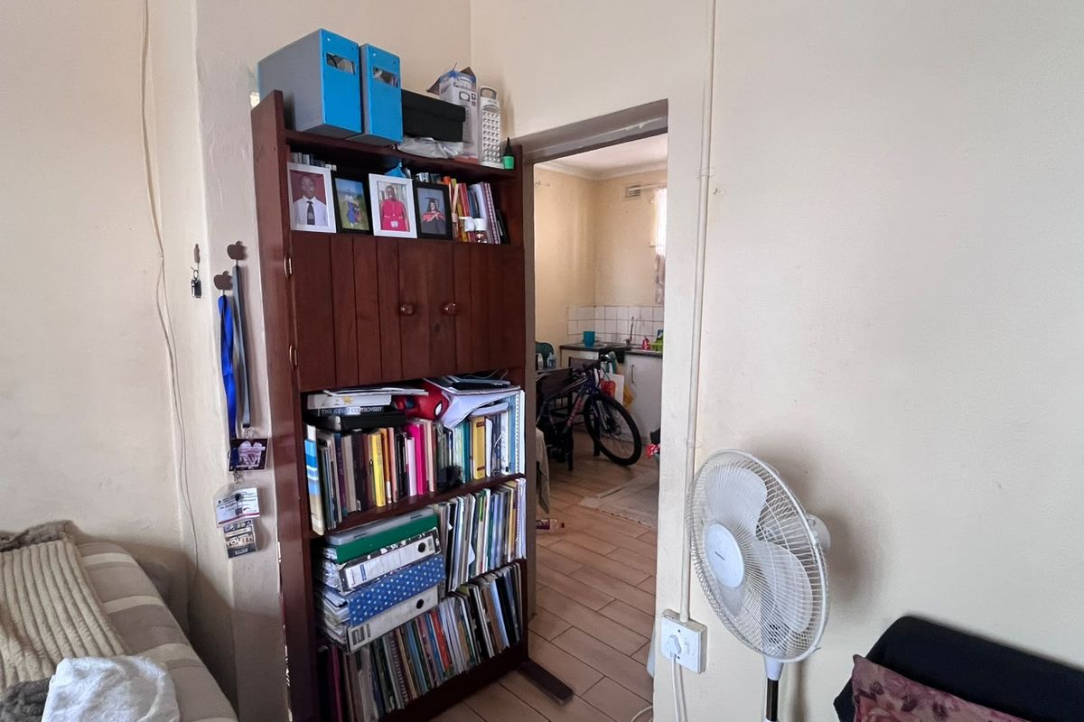 A view from a living area looking through a doorway into a kitchen space, featuring tiled flooring and visible electrical conduit.