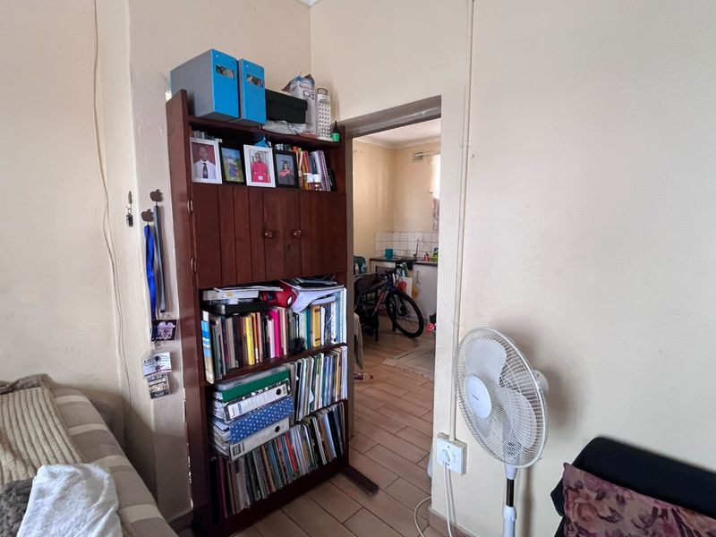 A view from a living area looking through a doorway into a kitchen space, featuring tiled flooring and visible electrical conduit.