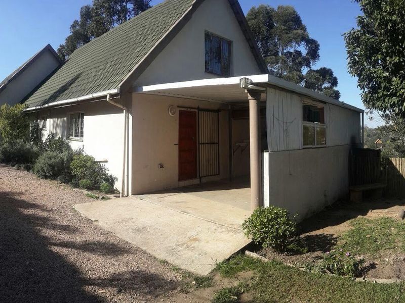 Exterior view of a townhouse featuring a pitched roof, a covered carport, and a concrete driveway entrance.