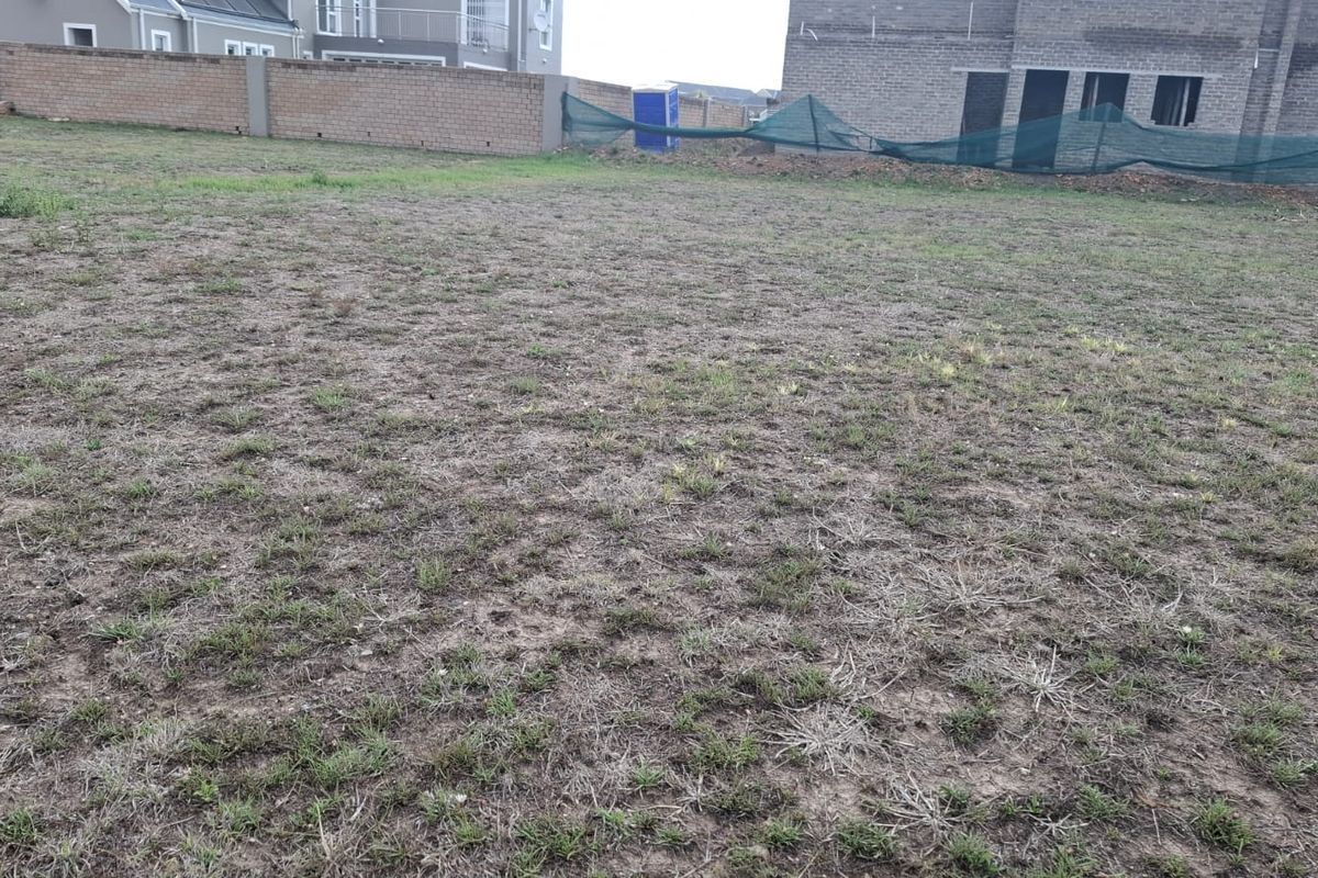 A vacant residential plot featuring a perimeter brick wall and temporary construction fencing, ready for development.