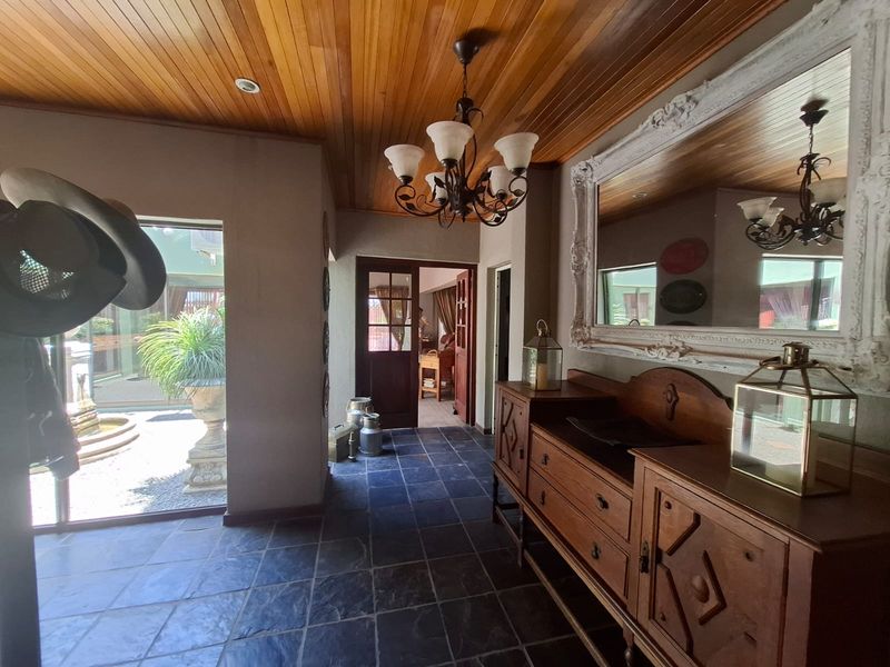 Welcoming entrance hall featuring a warm timber ceiling, durable slate flooring, and a classic wrought iron chandelier, providing access to the home's interior.