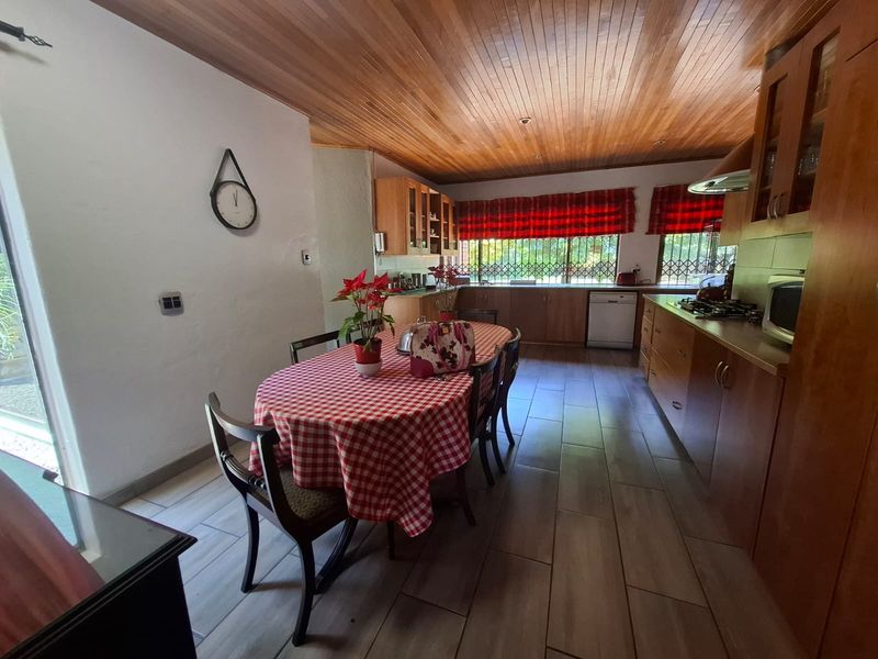 Open-plan kitchen and dining area featuring wooden cabinetry, tiled floors, a gas hob, and a distinctive timber-paneled ceiling.