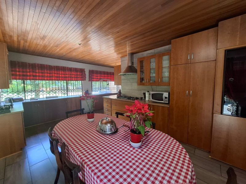 Open-plan kitchen and dining area featuring warm wooden cabinetry, a tongue and groove ceiling, and tiled flooring, offering a functional and traditional layout.
