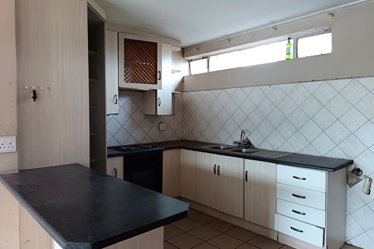 A dated kitchen featuring built-in cabinetry, laminate countertops, a double sink, and an integrated oven, requiring cosmetic updates to modernize the space.