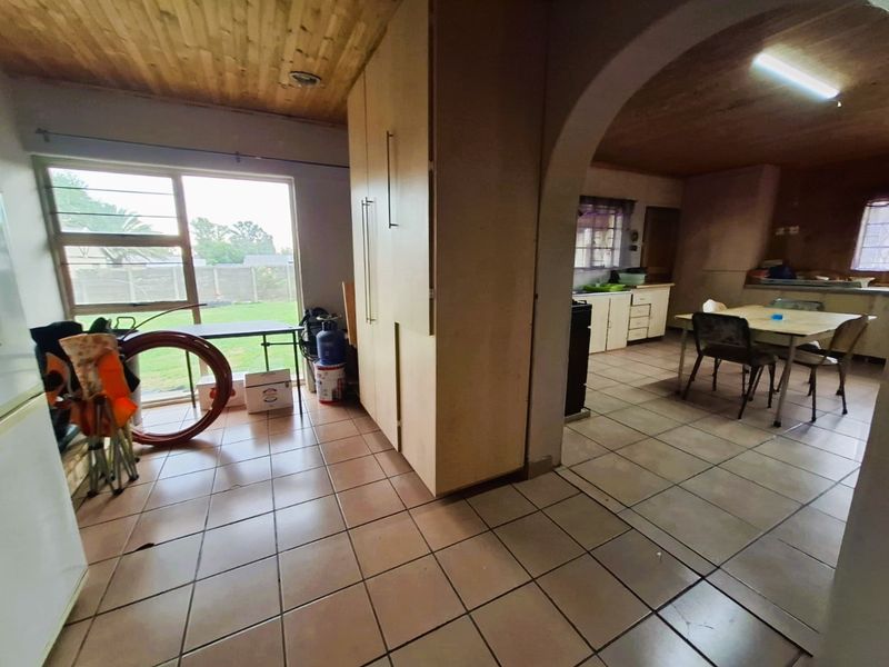 Open plan living and kitchen area featuring tiled flooring, timber ceilings, and an arched transition between spaces with direct access to the garden.