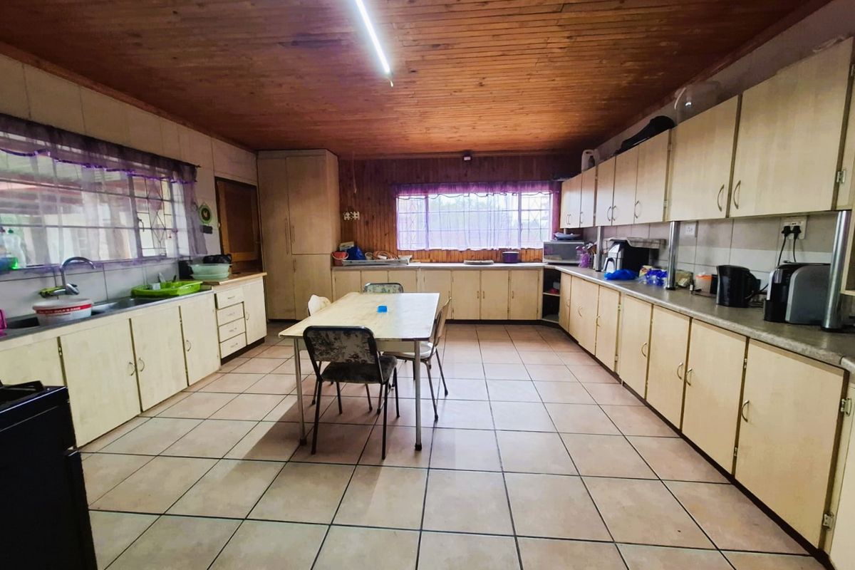 Spacious kitchen featuring extensive built-in cabinetry, laminate countertops, tiled flooring, and a timber-clad ceiling, offering significant potential for modernization.