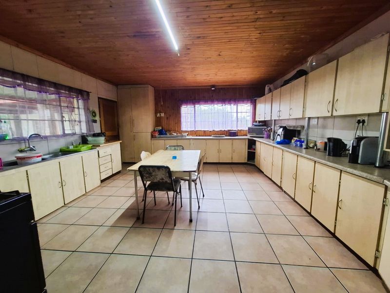 Spacious kitchen featuring extensive built-in cabinetry, laminate countertops, tiled flooring, and a timber-clad ceiling, offering significant potential for modernization.