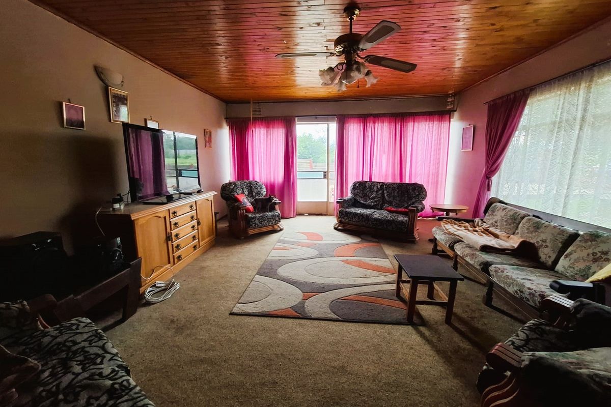 Spacious living room featuring a timber tongue and groove ceiling, ceiling fan, and direct access to the exterior via a sliding glass door.