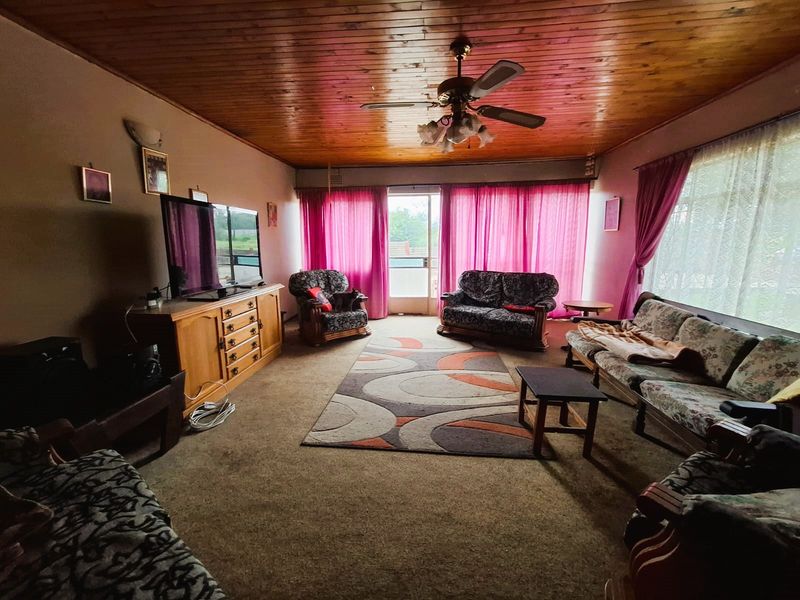 Spacious living room featuring a timber tongue and groove ceiling, ceiling fan, and direct access to the exterior via a sliding glass door.