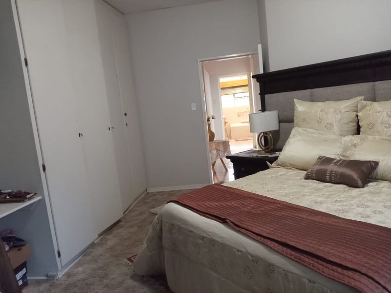 A bedroom featuring built-in cupboards and carpeted flooring, with an adjoining bathroom visible through the doorway.