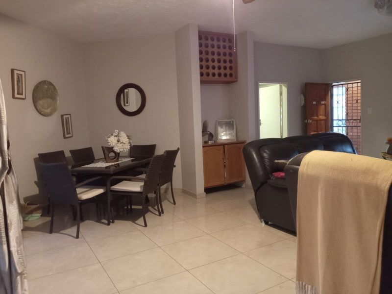 Open plan living and dining area featuring tiled flooring, built-in cabinetry with integrated wine storage, and access to a secure entrance.
