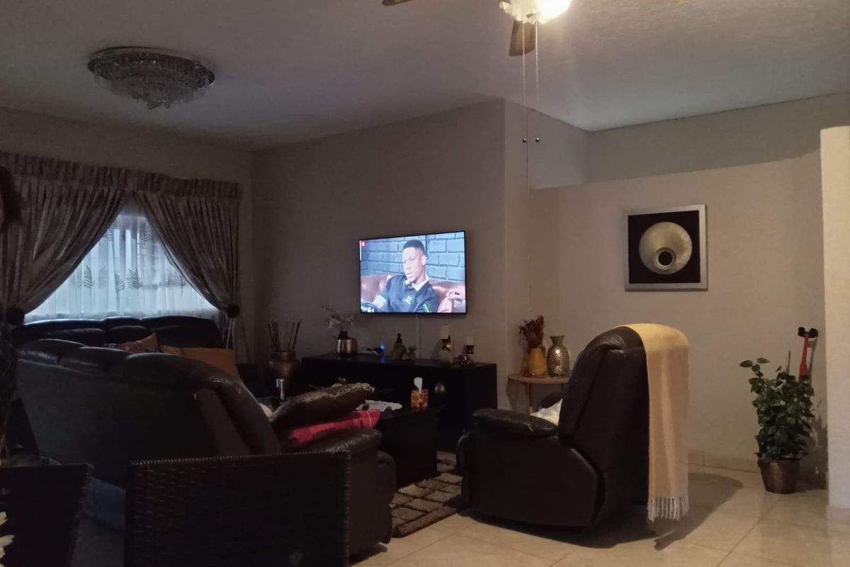 A comfortable living room featuring tiled flooring, a ceiling fan, and neutral wall finishes, providing a functional and inviting space for relaxation.