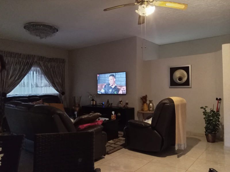 A comfortable living room featuring tiled flooring, a ceiling fan, and neutral wall finishes, providing a functional and inviting space for relaxation.