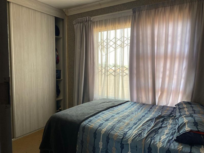 A bedroom featuring a built-in wardrobe with sliding doors, a window with a security gate, and decorative ceiling cornicing.