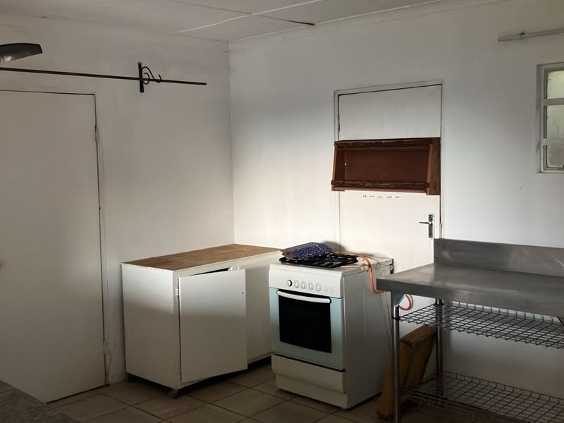 A basic, functional kitchen area featuring a gas stove, stainless steel prep station, and tiled flooring, offering potential for a modern renovation.
