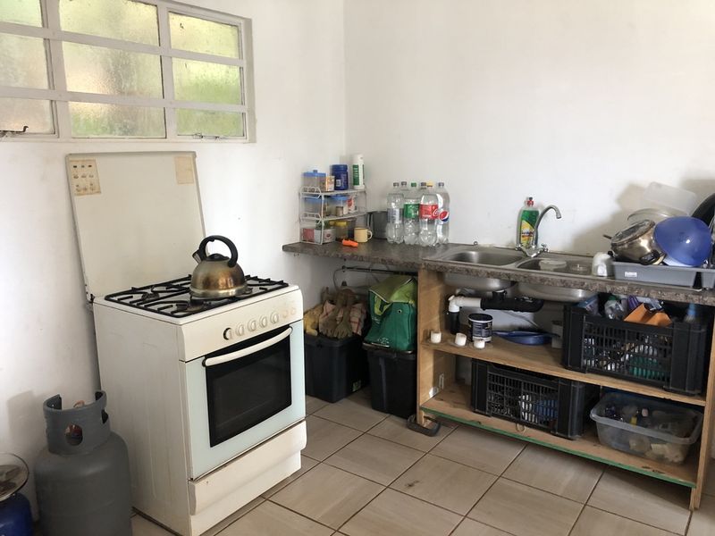 A functional kitchen area featuring a gas stove, double bowl sink, and open shelving with tiled flooring.