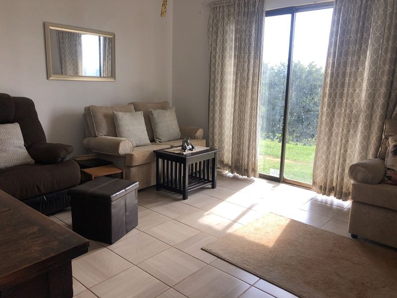 A living room featuring tiled flooring and a large sliding glass door providing natural light and access to the garden.