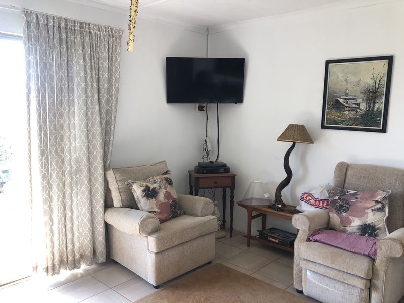 A cozy living room area featuring tiled flooring and a sliding glass door providing natural light.