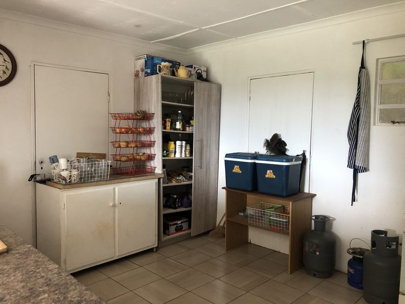 A functional scullery or utility area featuring tiled flooring and built-in storage cabinetry, offering practical space for food preparation and household storage.