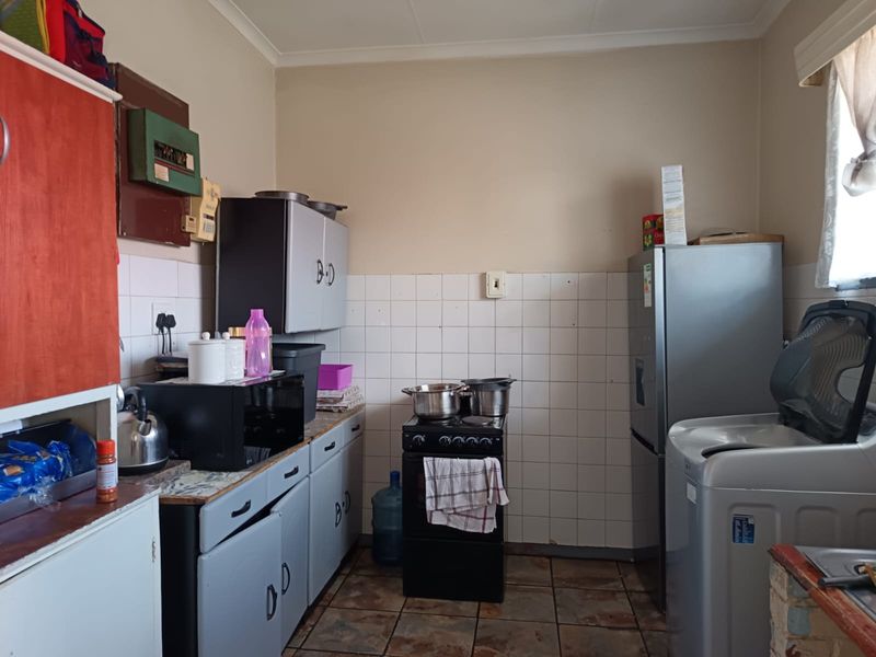 A functional kitchen featuring tiled flooring, a tiled backsplash, and built-in cabinetry, offering a practical layout with space for essential appliances.