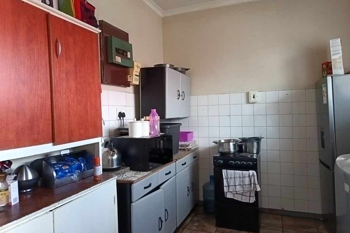 A functional kitchen featuring built-in cabinetry, tiled splashbacks, and tiled flooring, offering a dated aesthetic that could benefit from modern updates.