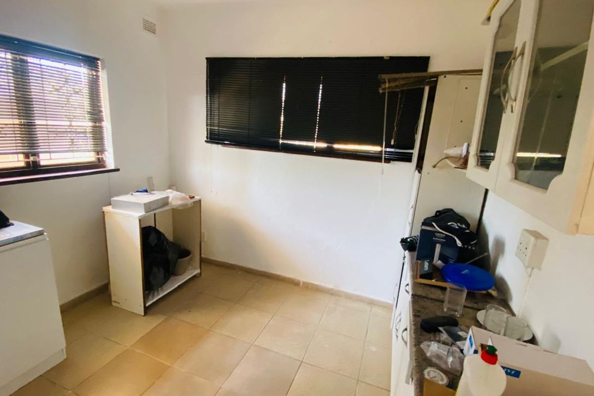 A dated kitchen area featuring tiled flooring, built-in cabinetry, and window blinds, requiring cosmetic updates and modernization to improve functionality and aesthetic appeal.