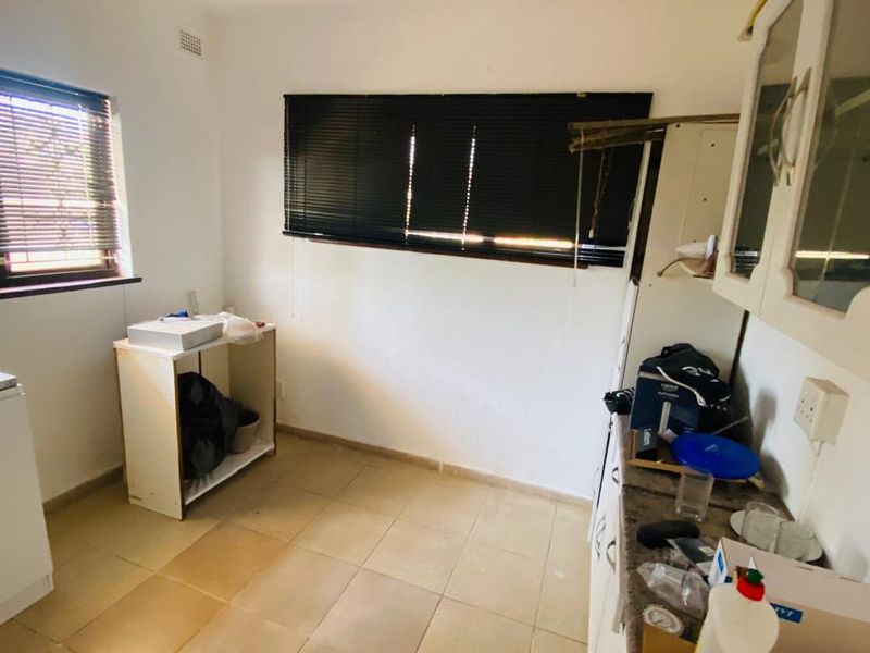A dated kitchen area featuring tiled flooring, built-in cabinetry, and window blinds, requiring cosmetic updates and modernization to improve functionality and aesthetic appeal.