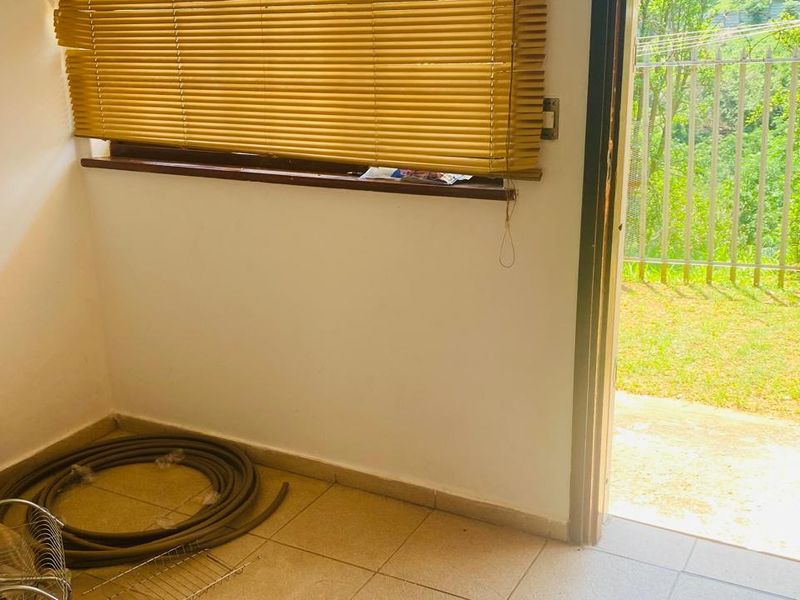 A functional laundry area featuring tiled flooring and direct access to the outdoor garden space through a secure door.