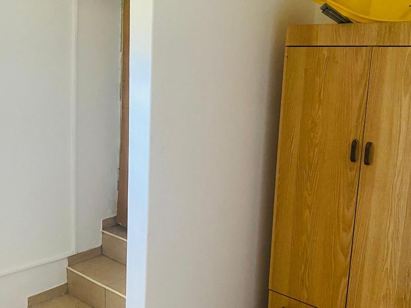 A narrow hallway area featuring a tiled staircase and basic wall finishes, showing signs of wear and tear.