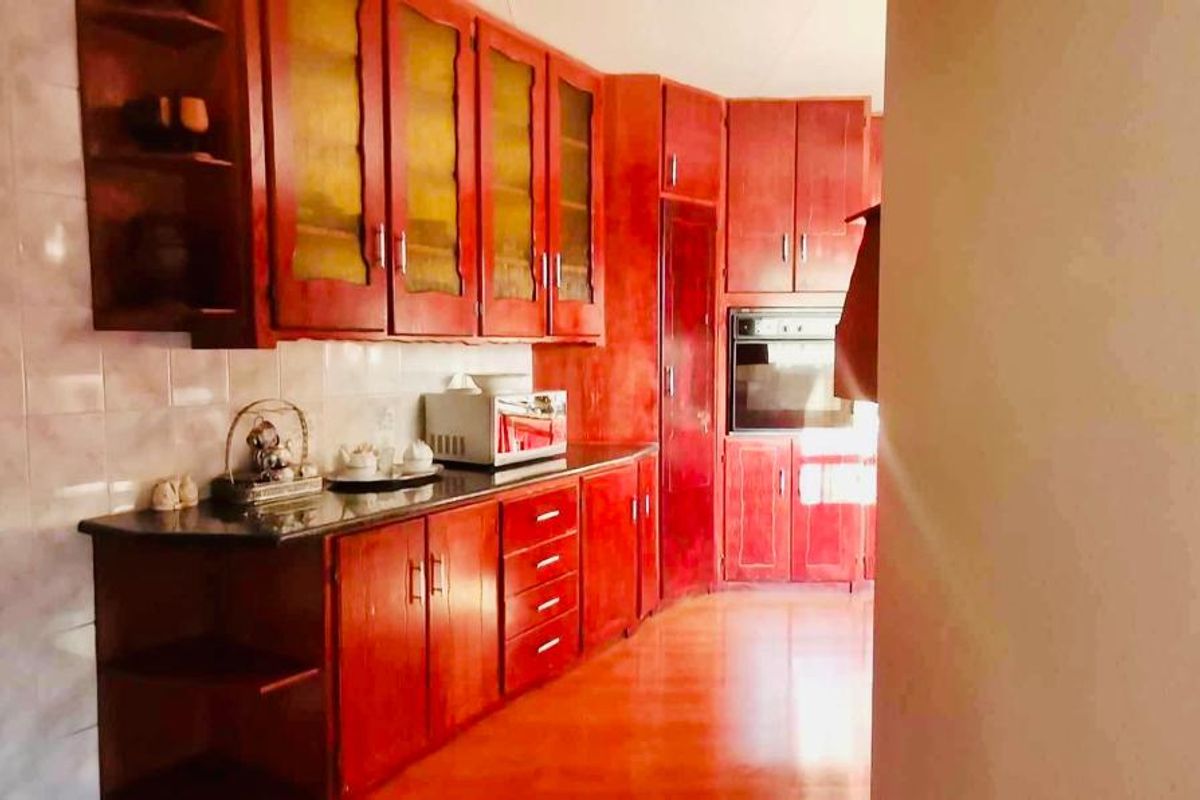 A functional kitchen featuring extensive built-in wooden cabinetry, granite countertops, and a built-in oven with tiled splashback finishes.