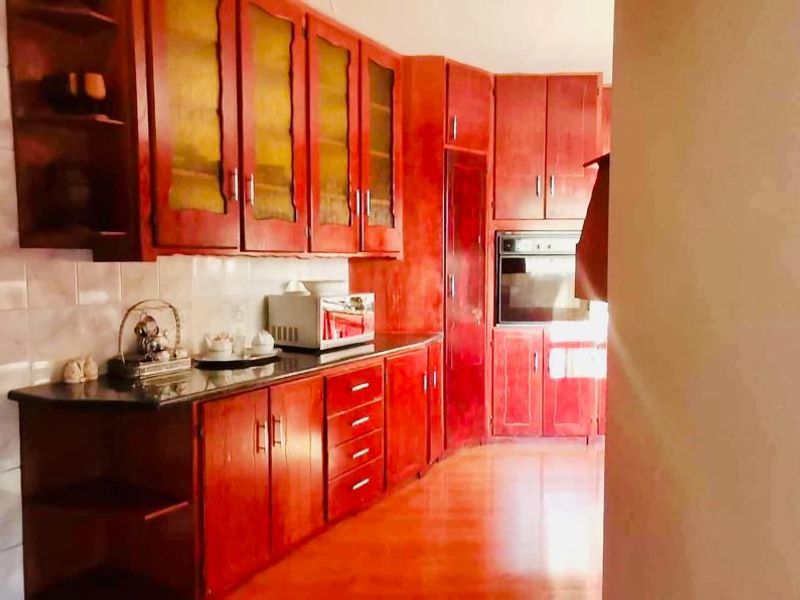A functional kitchen featuring extensive built-in wooden cabinetry, granite countertops, and a built-in oven with tiled splashback finishes.