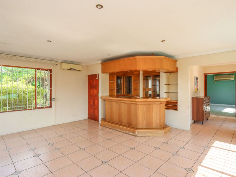A spacious room featuring a built-in wooden bar, tiled flooring, and split-system air conditioning, offering a versatile space for entertainment.