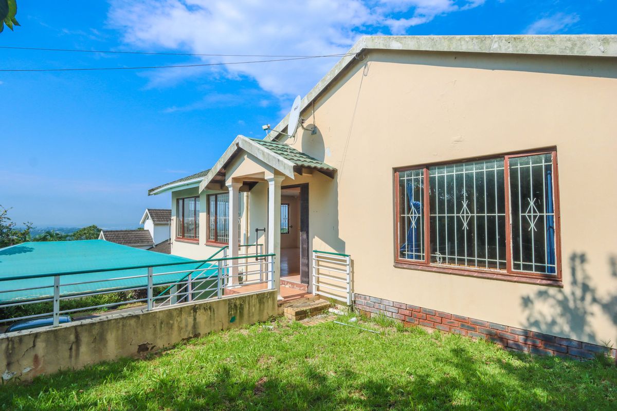 Rear exterior view of the house featuring a covered entrance, security bars on windows, and an adjacent carport structure.