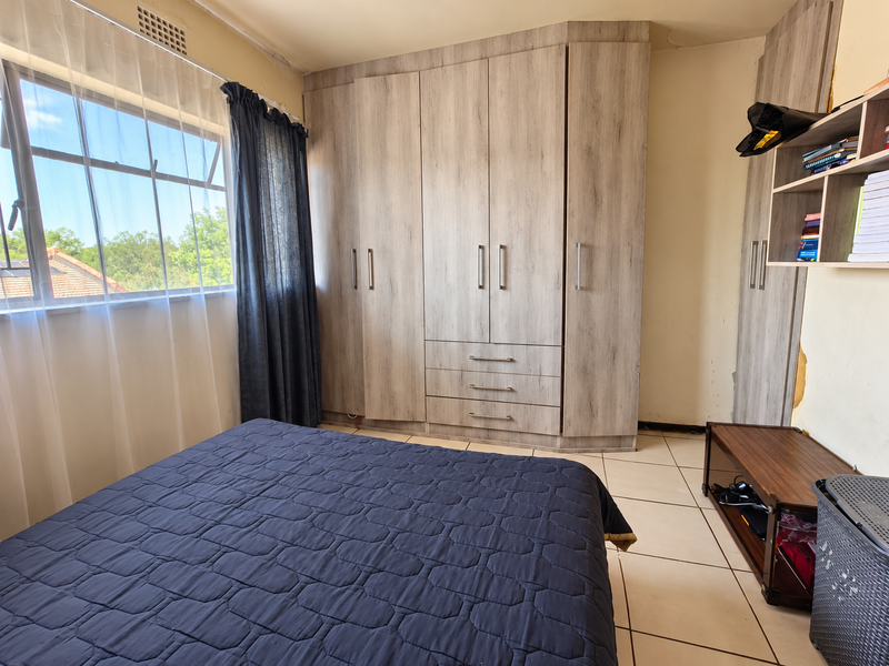 Bedroom featuring built-in wooden cupboards, tiled flooring, and a window with natural light. Requires minor wall repairs.