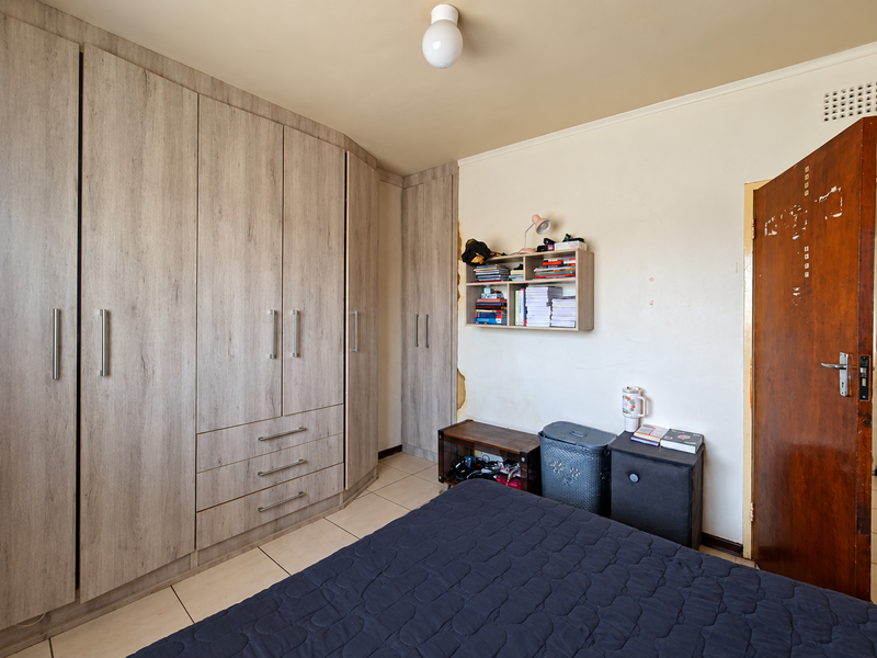 Bedroom featuring extensive built-in cupboards with wood-grain finish, tiled flooring, and a standard ceiling light fixture.