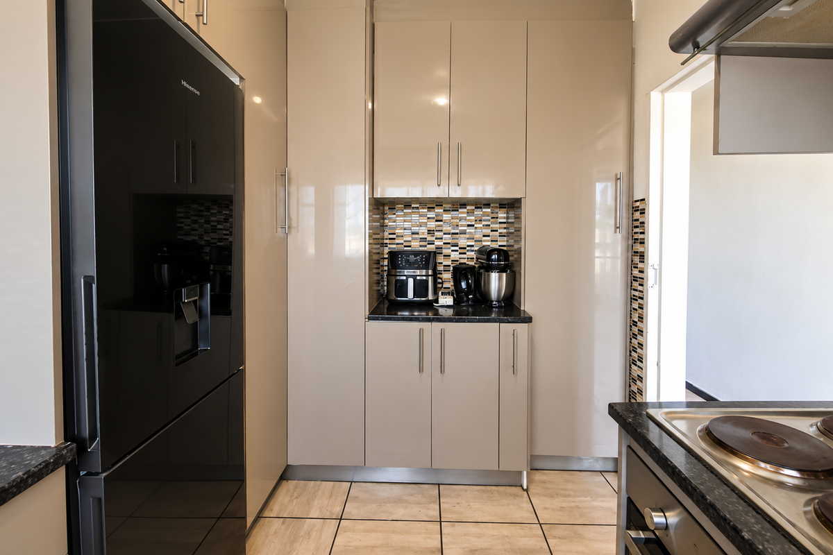 Modern kitchen featuring high-gloss cabinetry, granite countertops, mosaic tile backsplash, and integrated appliances including an oven and hob.