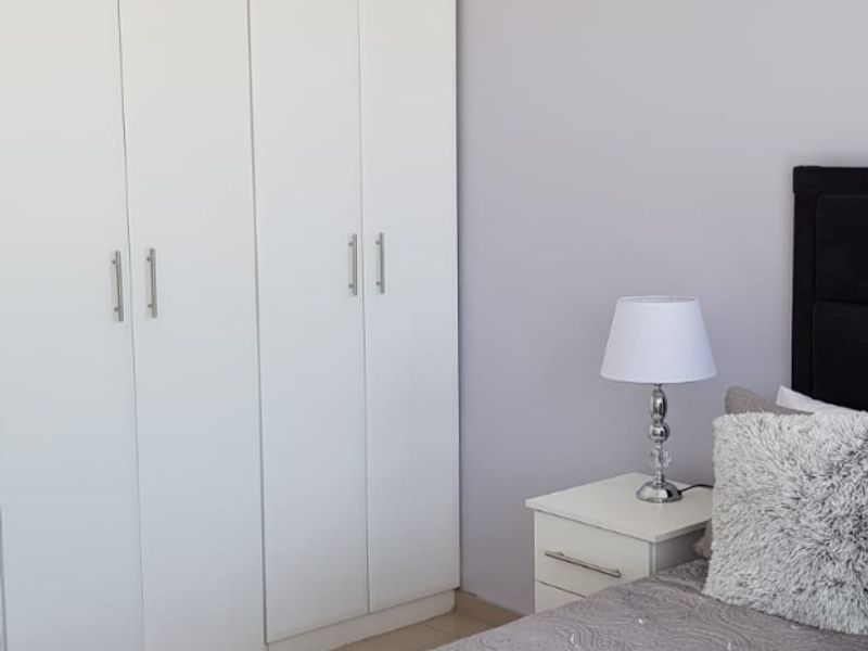 A well-maintained bedroom featuring floor-to-ceiling built-in cupboards and decorative ceiling coving.