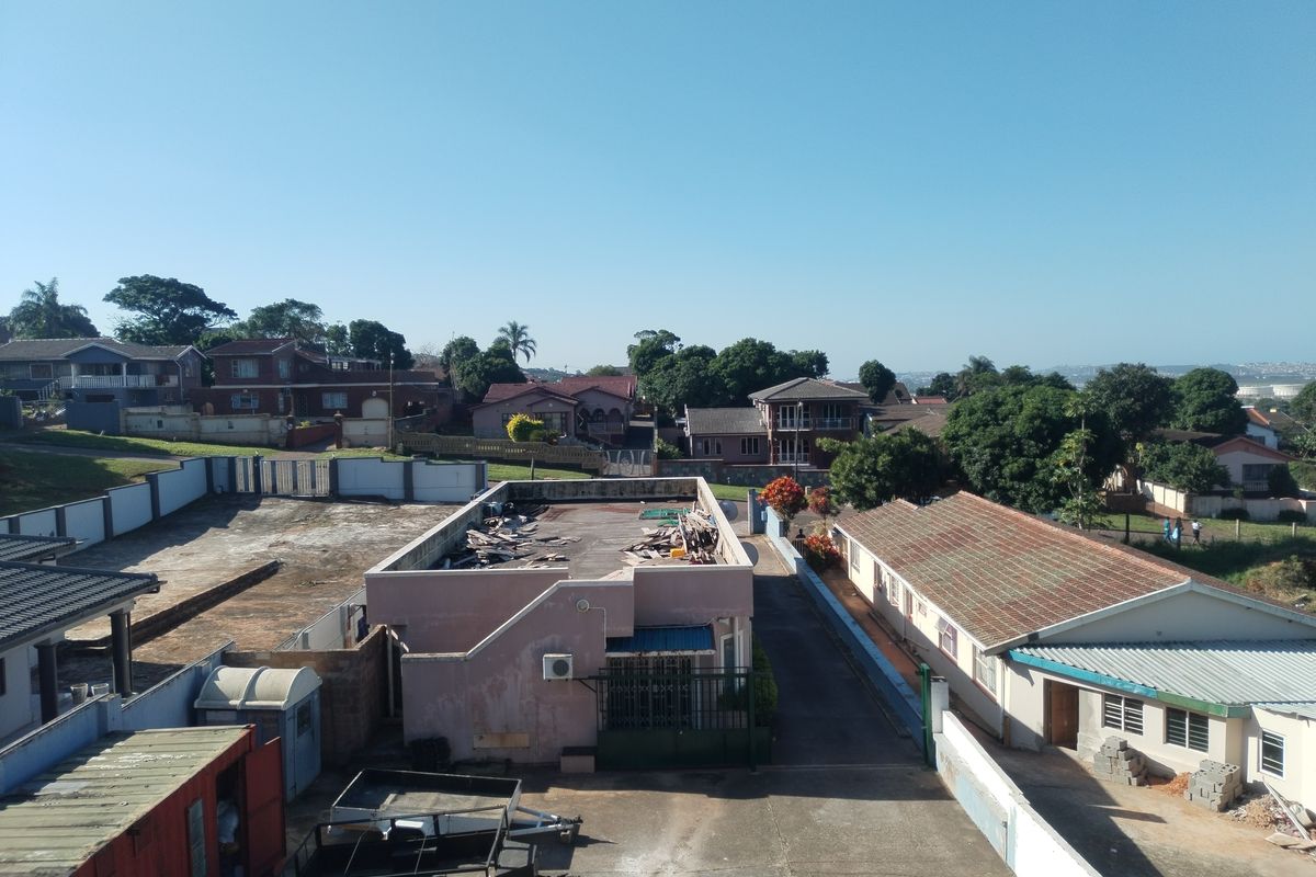 An elevated aerial view of a residential property showing multiple structures, paved driveway areas, and surrounding neighbourhood context.