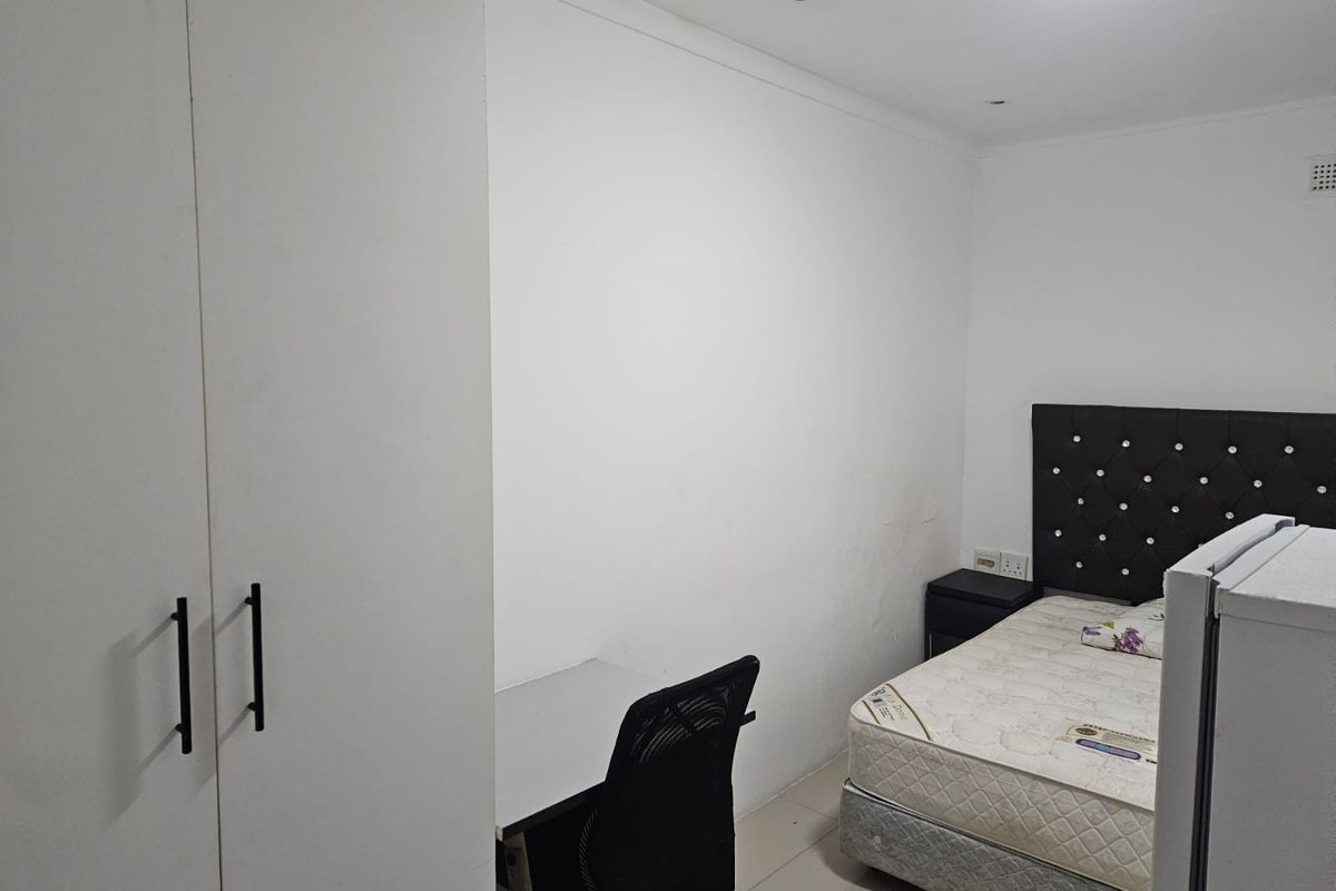 A functional bedroom featuring built-in wardrobes, tiled flooring, and recessed lighting, offering a clean and neutral space ready for personalization.