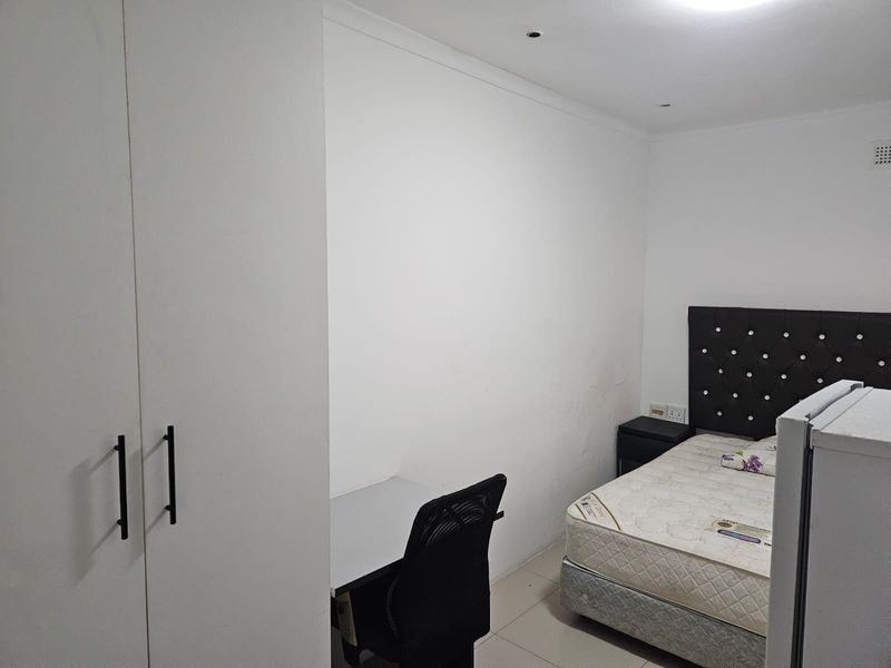 A functional bedroom featuring built-in wardrobes, tiled flooring, and recessed lighting, offering a clean and neutral space ready for personalization.