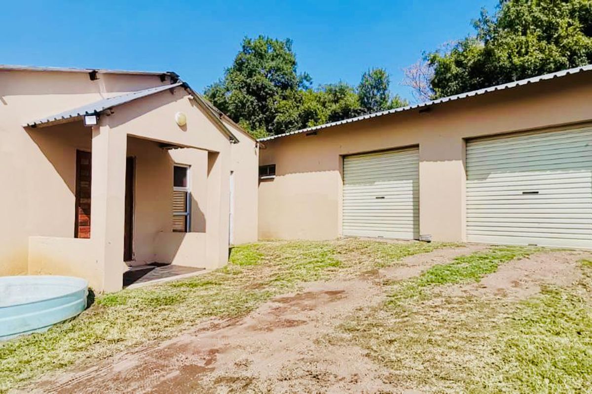 Rear view of the property featuring a double garage with roller doors, a covered entrance, and a small plunge pool set in a garden area.