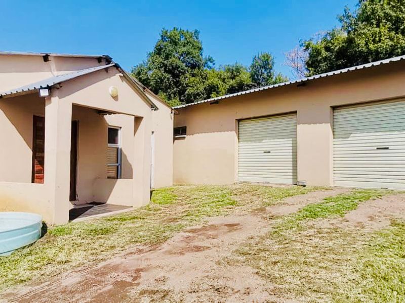 Rear view of the property featuring a double garage with roller doors, a covered entrance, and a small plunge pool set in a garden area.